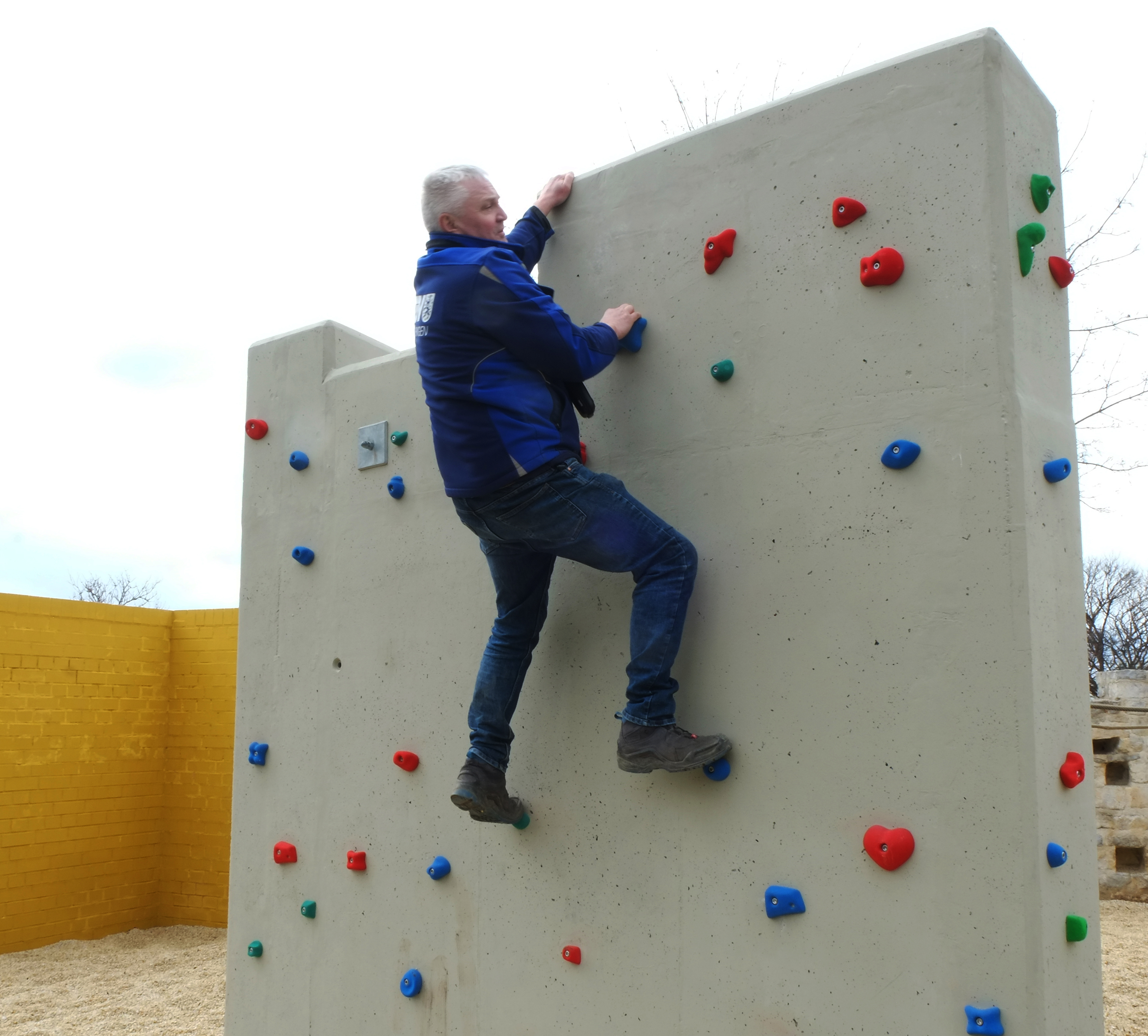 Spielplatzprüfer klettert an einer Kletterwand